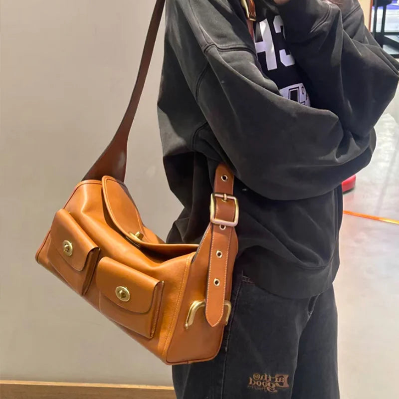 Person wearing a black hoodie and a brown PU leather shoulder bag with adjustable strap.