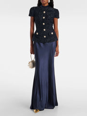 Woman wearing a navy two-piece set featuring a short-sleeve buttoned top and floor-length sheath skirt — elegant summer office or event outfit