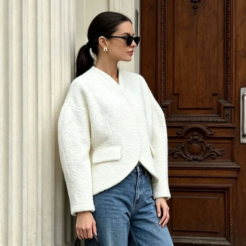 Close-up on the textured fabric of a white V-neck cropped blazer.
