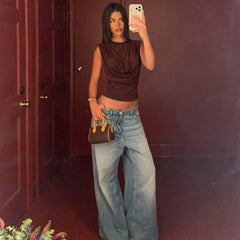 Person taking a mirror selfie wearing a brown top and blue jeans in a room with red walls.