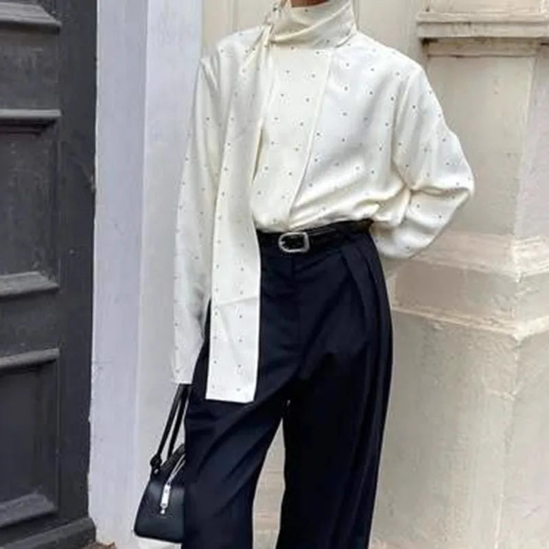 Close-up of a polka dot blouse featuring a high neckline and scarf accent