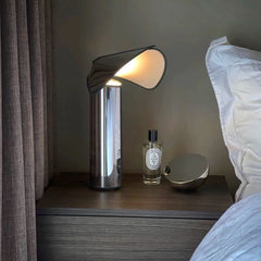 A cozy bedroom with a modern LED table lamp providing warm light on a bedside table. A