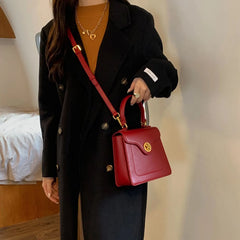 Person wearing a black coat carrying a red structured top handle bag
