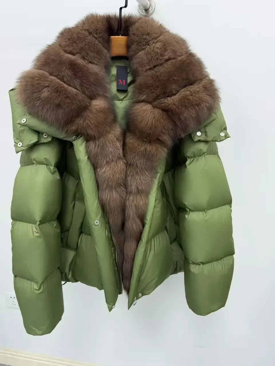 Green puffer jacket with brown fur collar on a white background