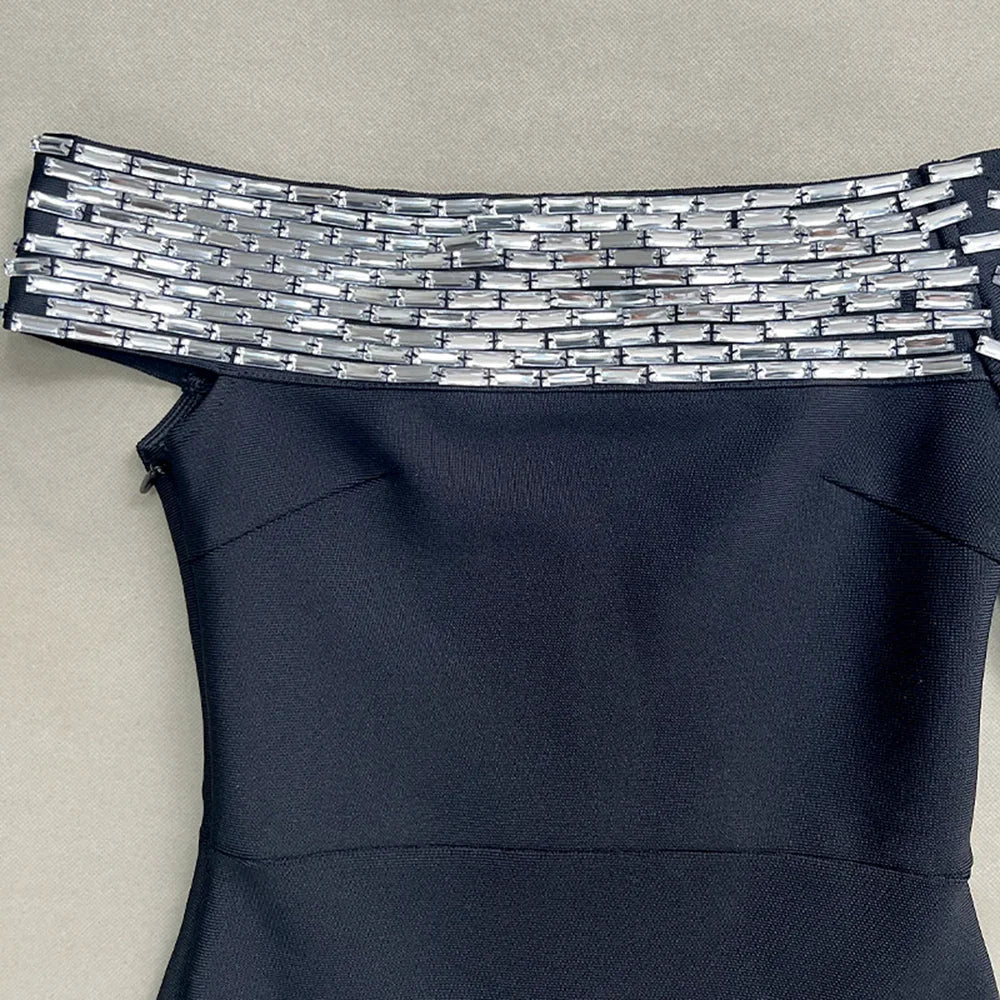 Black dress with a decorative silver waistband on a beige background