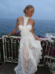 Woman in a white lace dress standing on a balcony with ocean view