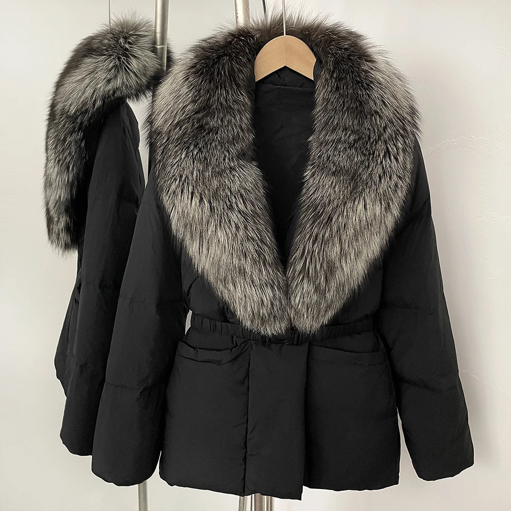 Black coat with large fur collar on a hanger against a white background