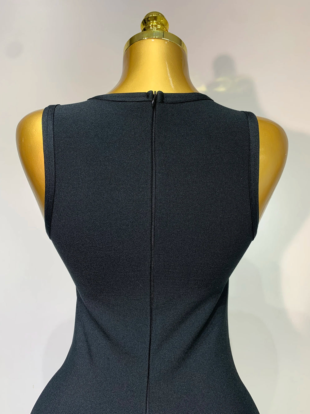 Black sleeveless dress on a mannequin with a plain background