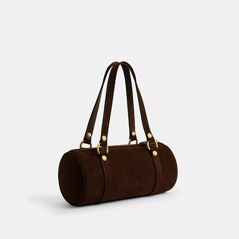 Brown leather handbag with gold hardware on a light gray background