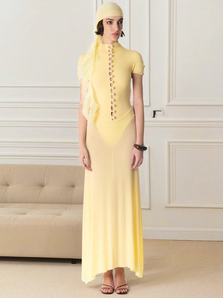 Woman wearing a yellow dress with a matching headscarf in an elegant room.