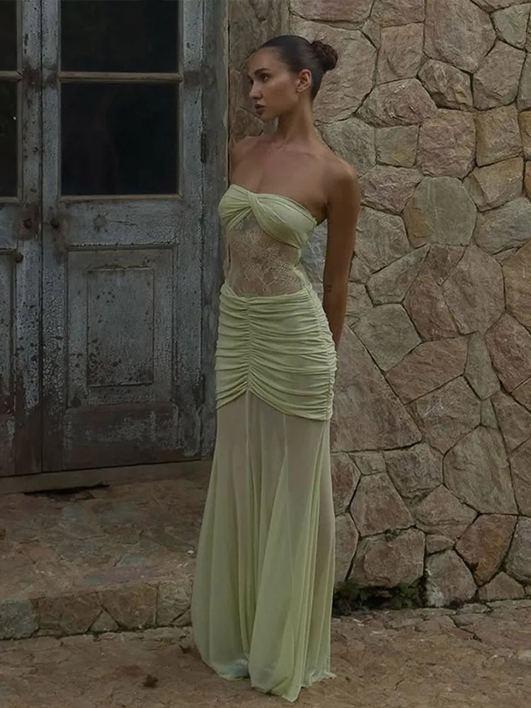 Woman in a light green strapless dress standing against a stone wall.