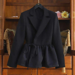 Black coat on a hanger against a wooden background with decorative elements.
