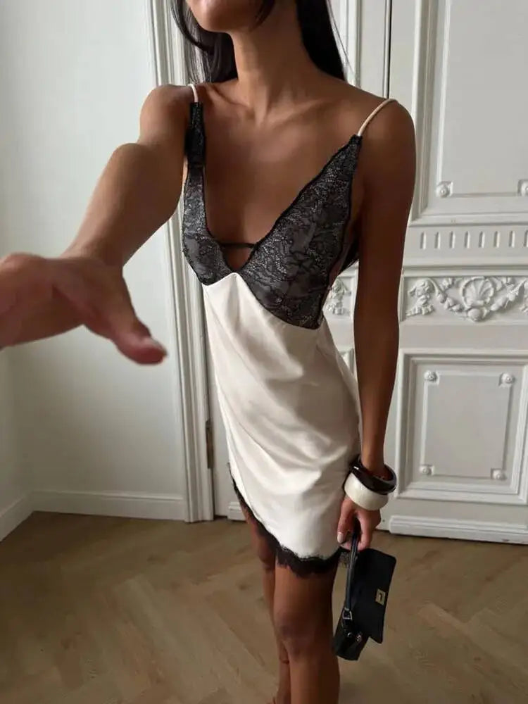 Woman wearing a white dress with black lace details in an elegant room.