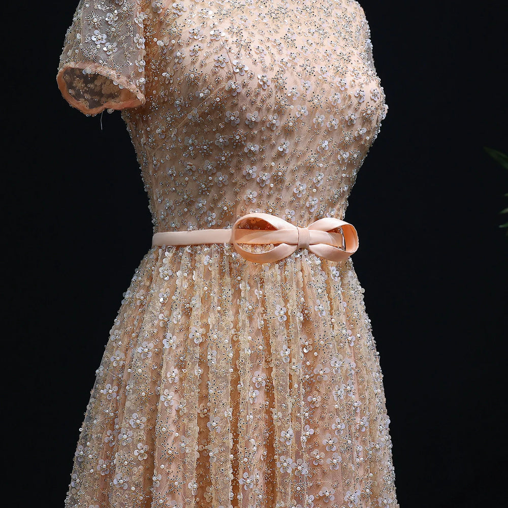Beige dress with floral embellishments and a pink bow on a black background