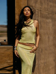 Woman in a green knit outfit standing against a wooden wall.