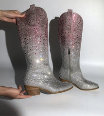 Silver glittery boots being held against a white background