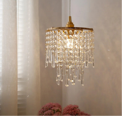 Crystal chandelier hanging in a room with curtains and flowers.