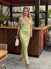 Woman in a green sequin dress standing in front of a bar counter.