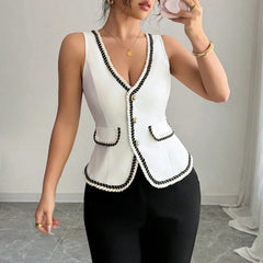 Woman wearing a white sleeveless top with black trim against a neutral background