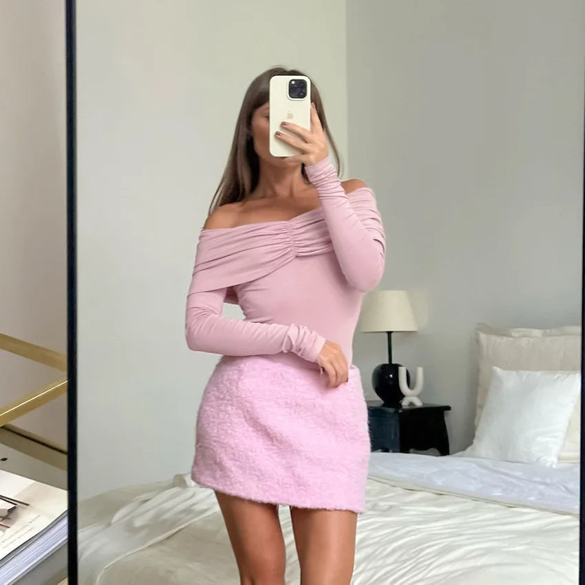 Person wearing a pink off-shoulder dress in a bedroom setting.