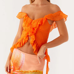 Orange off-shoulder top worn by a person on a white background