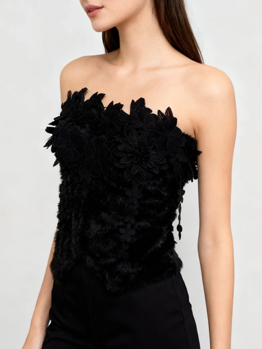 Black strapless top with floral details on a plain background