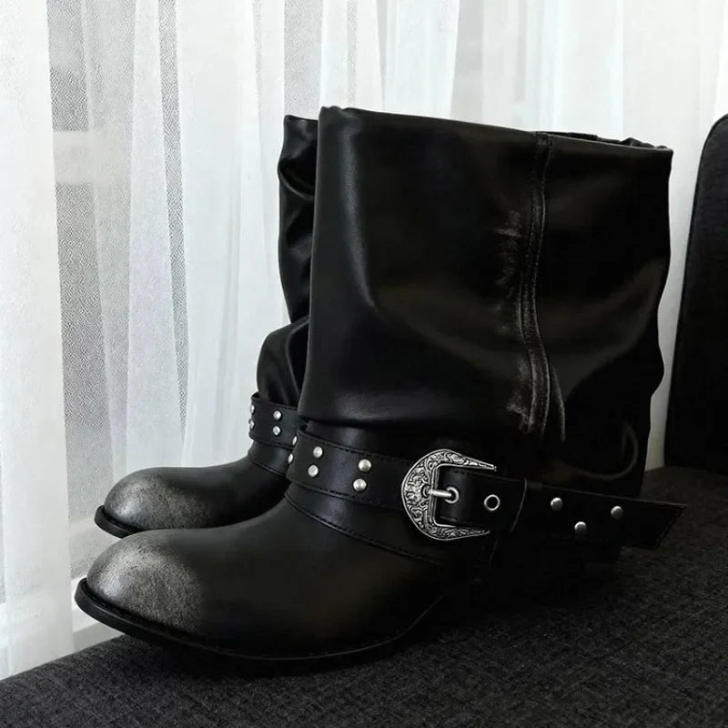 Black slouch ankle boots with a distressed metallic toe cap and decorative buckle strap.