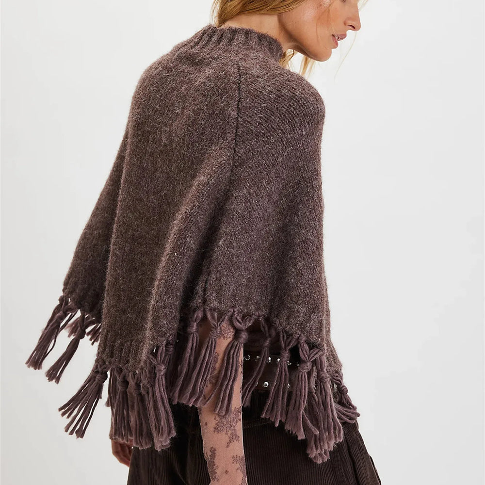 Brown knitted poncho with fringe details on a plain background