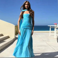 Woman in a blue strapless gown standing on a balcony with ocean view