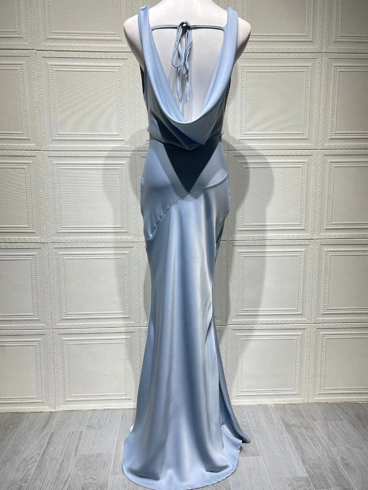 Blue evening gown on a mannequin against a white paneled wall.