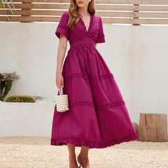 Woman wearing a magenta dress with a pearl-handled bag outdoors.