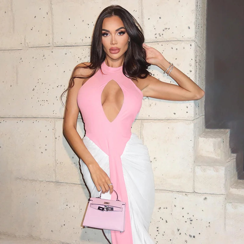Woman in a pink and white dress holding a matching handbag against a stone wall.