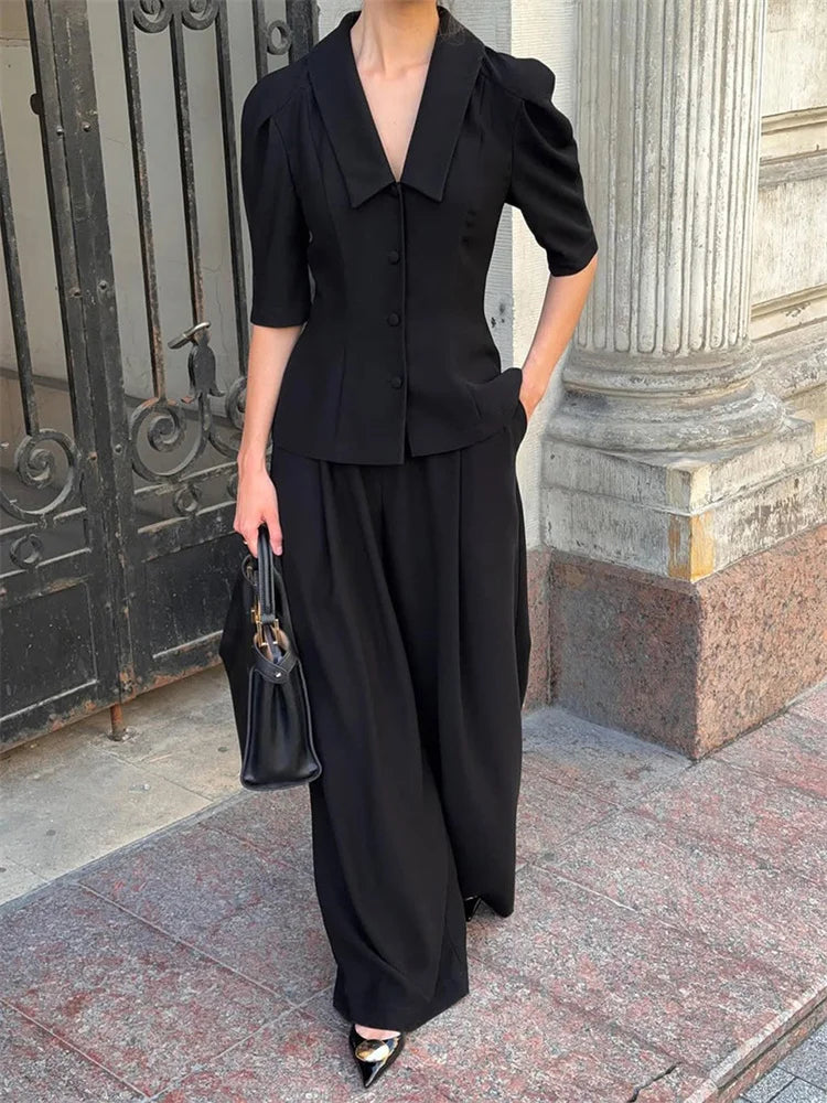 Person wearing a black outfit standing in front of classical architecture.