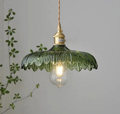 Close-up of a vintage green glass pendant lamp, showcasing the textured glass and warm glow of the LED bulb. a