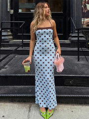 Woman in a polka dot dress standing on a city street.