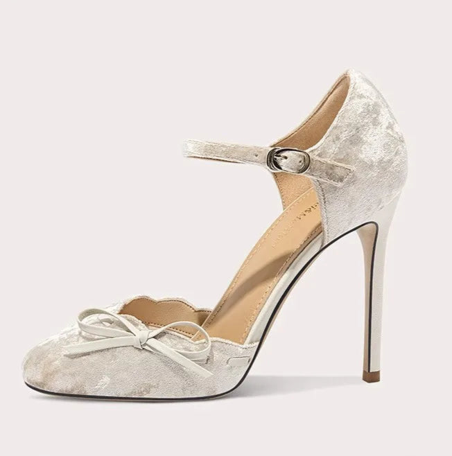 Silver high-heeled shoe with a bow on a white background