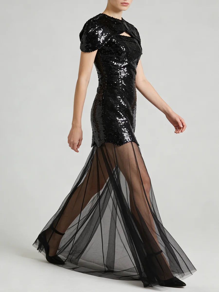 Black sequin mini dress with sheer tulle maxi overlay, model walking.