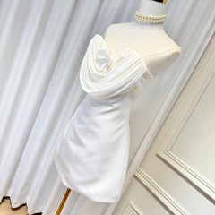 White strapless mini dress on mannequin with sculpted rose applique and draped front