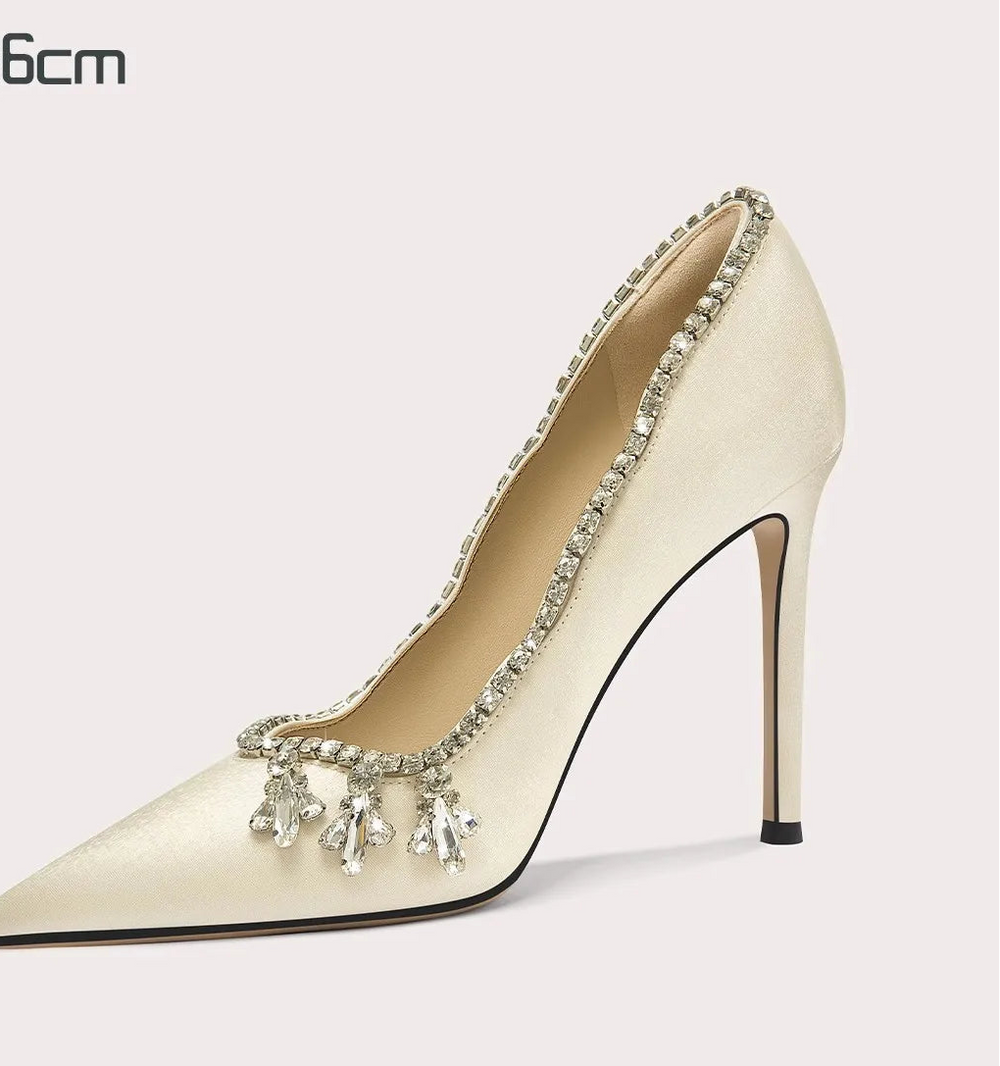 Beige high-heeled shoe with decorative elements on a white background