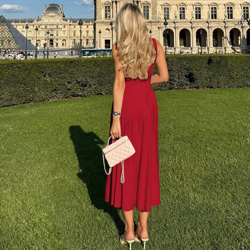 Woman in a red dress standing on grass with a historic building in the background