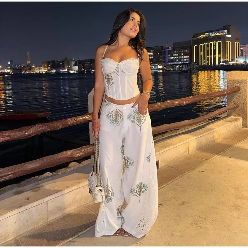 Floral print corset top and wide leg pants set on a model at night by the water.