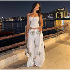 Floral print corset top and wide leg pants set on a model at night by the water.