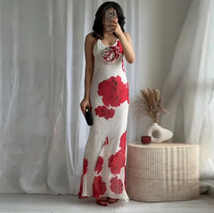 Woman taking a mirror selfie wearing a white dress with red floral patterns in a minimalistic room.