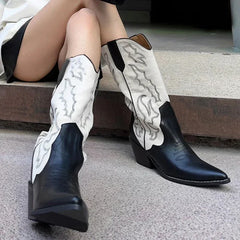 Black and white cowboy boots worn by a person sitting on a step.