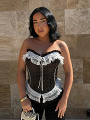 Black polka dot corset top with white lace trim and sweetheart neckline.