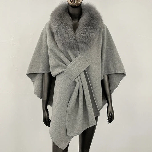 Grey knit poncho with a grey fur collar and knotted front.