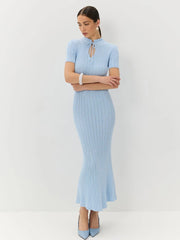 Woman wearing a light blue ribbed dress with a slit on a white background
