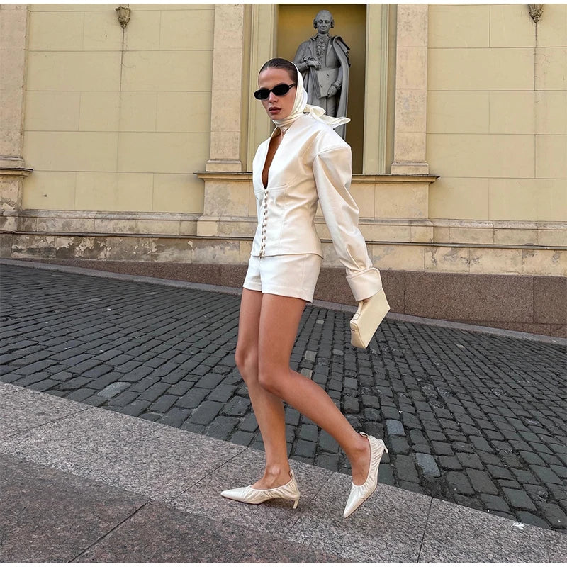 Woman in a white outfit walking on a street with a classical building in the background