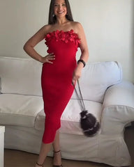 Woman in a red dress with floral details standing in a room with a white couch.