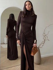 Woman in a brown dress standing in front of a mirror, holding a brown handbag.
